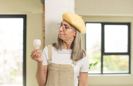 Photo for Pretty senior woman smiling and looking with a happy confident expression. with a light bulb - Royalty Free Image