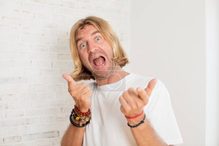 Photo for Young blond adult man feeling happy, cool, satisfied, relaxed and successful, pointing at camera, choosing you - Royalty Free Image