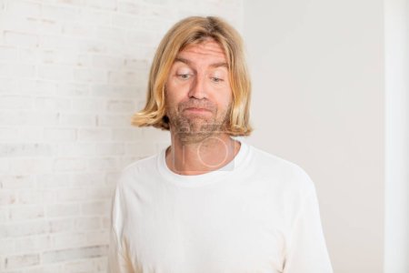 Photo for Young blond adult man feeling stressed, unhappy and frustrated, touching forehead and suffering migraine of severe headache - Royalty Free Image