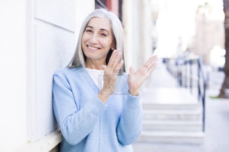 Photo for Senior retired pretty white hair woman feeling happy and successful, smiling and clapping hands, saying congratulations with an applause - Royalty Free Image