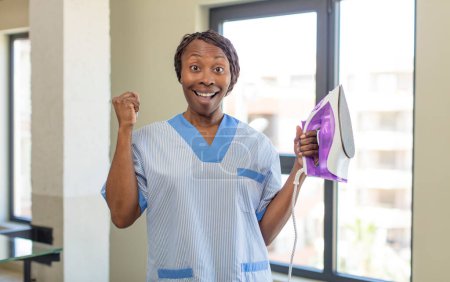 Foto de Negro afro mujer sintiéndose sorprendido, riendo y celebrando el éxito. concepto de lavandería y limpieza - Imagen libre de derechos