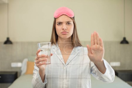 Photo for Young pretty woman looking serious showing open palm making stop gesture. water glass concept - Royalty Free Image