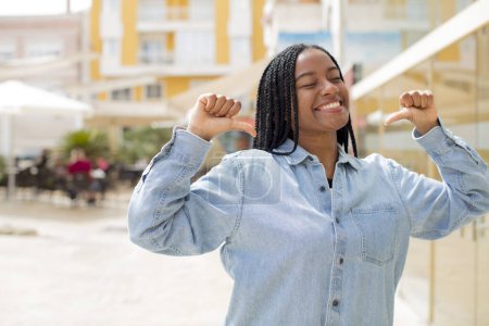 Téléchargez les photos : Afro jolie femme noire se sentant fier, arrogant et confiant, regardant satisfait et réussi, pointant vers soi-même - en image libre de droit