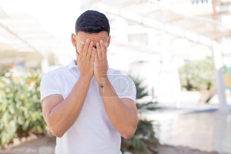 Photo for Young handsome man feeling sad, frustrated, nervous and depressed, covering face with both hands, crying - Royalty Free Image