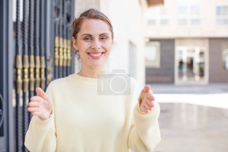 Foto de Mujer joven y bonita sosteniendo un objeto con ambas manos en el espacio de copia, mostrando, ofreciendo o haciendo publicidad de un objeto - Imagen libre de derechos