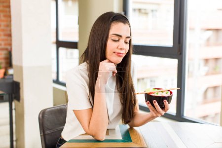 Photo for Pretty young woman eating chinese ramen noodles bowl. house interior design - Royalty Free Image