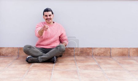 Foto de Joven hombre guapo sentado en los pisos con un espacio de copia - Imagen libre de derechos