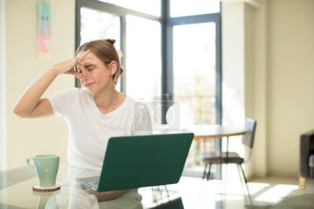 Photo for Caucasian pretty woman with a laptop feeling disgusted, holding nose to avoid smelling a foul and unpleasant stench - Royalty Free Image