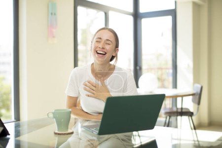 Foto de Mujer guapa caucásica con un ordenador portátil riendo en voz alta en alguna broma hilarante, sentirse feliz y alegre, divertirse - Imagen libre de derechos