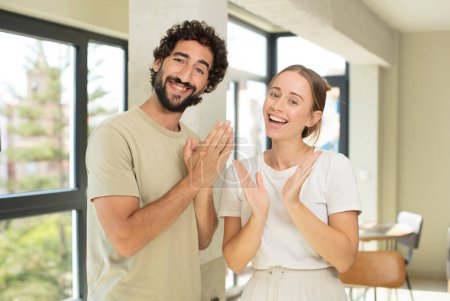 Téléchargez les photos : Jeune couple adulte se sentant heureux et réussi, souriant et applaudissant les mains, disant félicitations avec un applaudissement - en image libre de droit