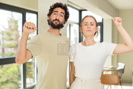 Photo for Young adult couple feeling serious, strong and rebellious, raising fist up, protesting or fighting for revolution - Royalty Free Image
