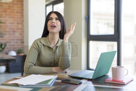 Photo for Pretty young woman screaming with hands up in the air. laptop and desk concept - Royalty Free Image