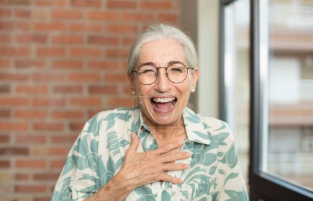 Foto de Senior bonita mujer riendo en voz alta en algún chiste hilarante, sentirse feliz y alegre, divertirse - Imagen libre de derechos