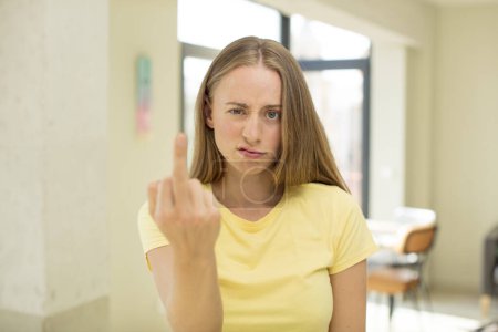 Foto de Bonita mujer rubia sintiéndose enojada, molesta, rebelde y agresiva, volteando el dedo medio, luchando - Imagen libre de derechos