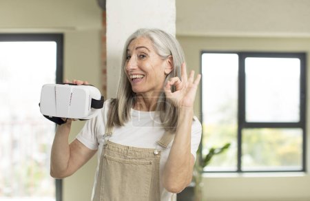 Photo for Pretty senior woman feeling happy, showing approval with okay gesture. with vr goggles - Royalty Free Image