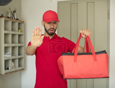 Photo for Young  adult man looking serious showing open palm making stop gesture. pizza deliveryman concept - Royalty Free Image