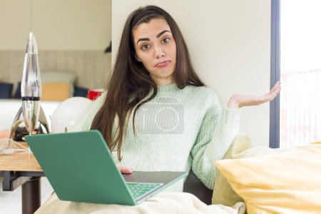 Téléchargez les photos : Jolie jeune femme travaillant à la maison avec un ordinateur portable. design intérieur de la maison - en image libre de droit