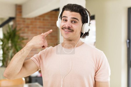 Foto de Joven hombre guapo escuchando música con auriculares en el interior de casa - Imagen libre de derechos