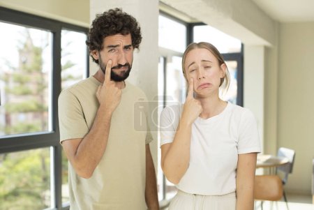 Photo for Young adult couple looking desperate and frustrated, sad, unhappy and crying - Royalty Free Image
