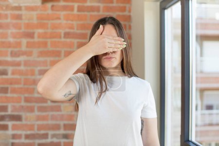 Photo for Young adult pretty woman covering eyes with one hand feeling scared or anxious, wondering or blindly waiting for a surprise - Royalty Free Image