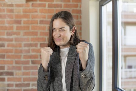 Téléchargez les photos : Young adult pretty woman looking confident, angry, strong and aggressive, with fists ready to fight in boxing position - en image libre de droit