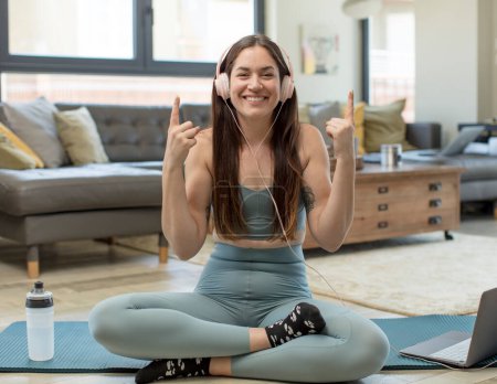 Téléchargez les photos : Jeune femme adulte pratiquant le yoga se sentant impressionné et bouche ouverte pointant vers le haut avec un regard choqué et surpris - en image libre de droit