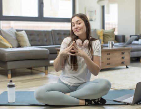 Téléchargez les photos : Jeune femme adulte pratiquant le yoga comploter et conspirer, penser astuces sournoises et tricheurs - en image libre de droit