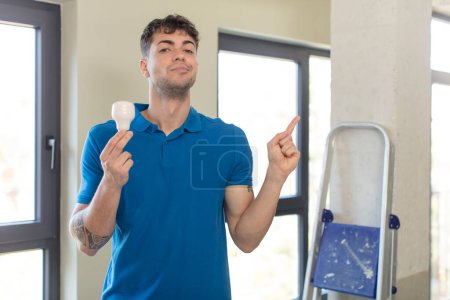 Photo for Young handsome man smiling cheerfully, feeling happy and pointing to the side. handyman concept - Royalty Free Image