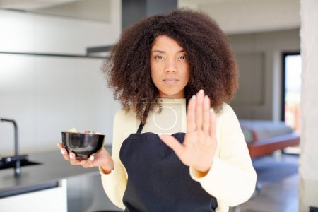 Photo for Pretty afro black woman looking serious showing open palm making stop gesture. japanese noodles ramen concept - Royalty Free Image