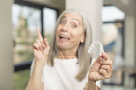 Foto de Mujer bastante mayor sintiéndose como un genio feliz y emocionado después de darse cuenta de una idea. con un retenedor dental - Imagen libre de derechos