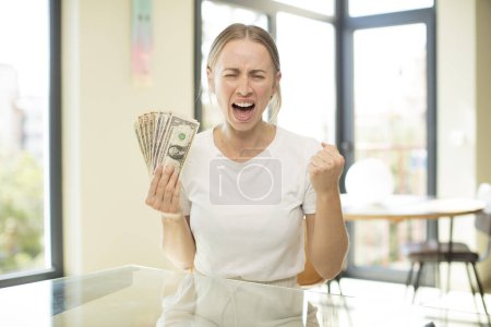 Foto de Joven mujer bastante caucásica mirando enojado, molesto y frustrado. concepto de billetes en dólares - Imagen libre de derechos