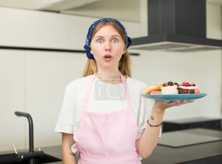 Téléchargez les photos : Young pretty woman feeling extremely shocked and surprised. home made cakes concept - en image libre de droit