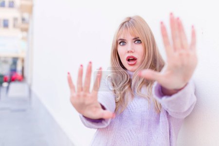 Photo for Young pretty woman feeling terrified, backing off and screaming in horror and panic, reacting to a nightmare - Royalty Free Image