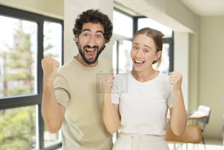 Téléchargez les photos : Jeune couple adulte se sentant choqué, excité et heureux, riant et célébrant le succès, disant wow! - en image libre de droit