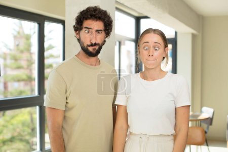 Photo for Young adult couple feeling stressed, unhappy and frustrated, touching forehead and suffering migraine of severe headache - Royalty Free Image