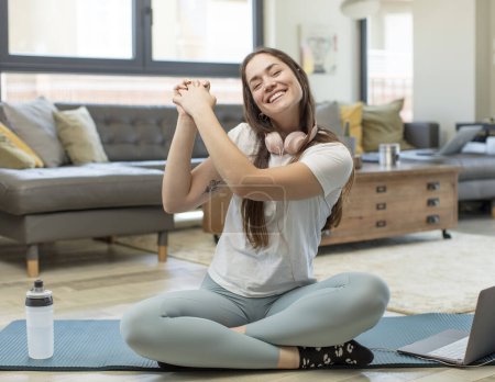 Foto de Joven mujer adulta practicando yoga sintiéndose feliz, sorprendida y orgullosa, gritando y celebrando el éxito con una gran sonrisa - Imagen libre de derechos