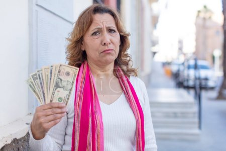 Foto de Mujer bonita de mediana edad sintiéndose triste y quejumbrosa con una mirada infeliz y llorando. concepto de billetes en dólares - Imagen libre de derechos