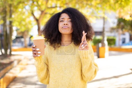 Foto de Mujer negra bastante afro cruzando los dedos y esperando buena suerte. quitar el concepto de café - Imagen libre de derechos