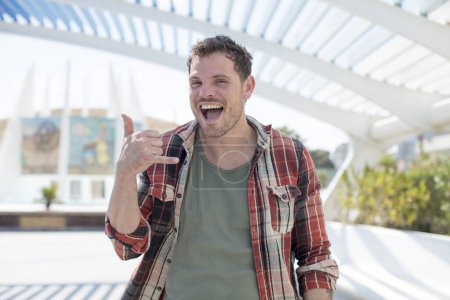 Photo for Handsome man crazy happily and cheerfully, waving hand, welcoming and greeting you, or saying goodbye - Royalty Free Image