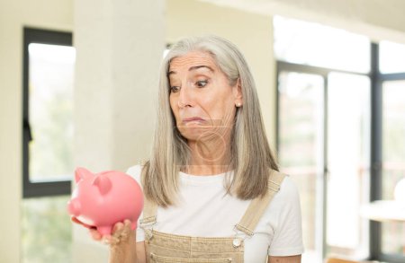 Photo for Pretty senior woman smiling and looking with a happy confident expression. with a piggy bank - Royalty Free Image