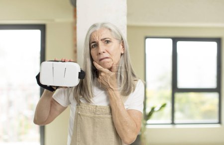 Photo for Pretty senior woman with mouth and eyes wide open and hand on chin. with vr goggles - Royalty Free Image