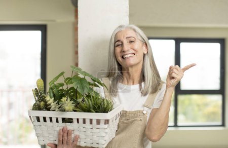 Photo for Pretty senior woman smiling cheerfully, feeling happy and pointing to the side. gardener concept - Royalty Free Image