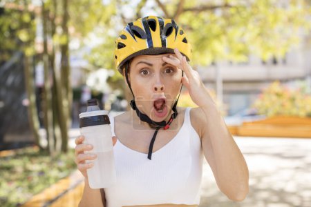 Photo for Young pretty woman looking happy, astonished and surprised. bike helmet concept - Royalty Free Image