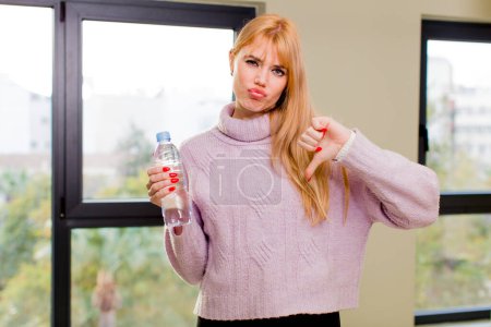 Téléchargez les photos : Jeune jolie femme avec une bouteille d'eau à l'intérieur de la maison - en image libre de droit