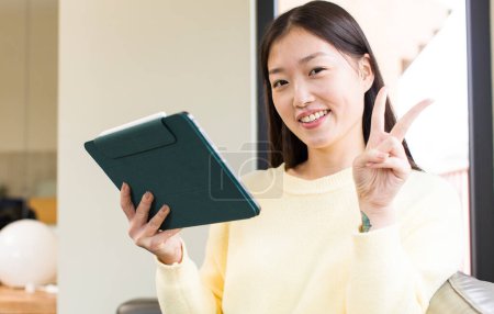 Téléchargez les photos : Asiatique jolie femme à l'aide d'un tactile pad - en image libre de droit