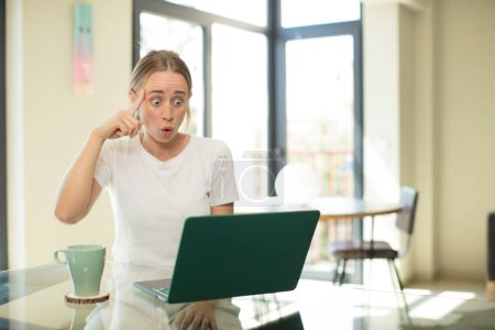 Photo for Caucasian pretty woman with a laptop looking surprised, open-mouthed, shocked, realizing a new thought, idea or concept - Royalty Free Image