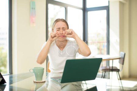 Foto de Mujer guapa caucásica con un ordenador portátil que parece desesperado y frustrado, estresado, infeliz y molesto, gritando y gritando - Imagen libre de derechos