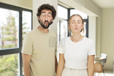 Photo for Young adult couple pressing lips together with a cute, fun, happy, lovely expression, sending a kiss - Royalty Free Image