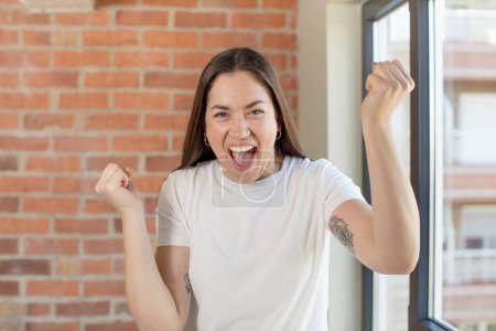 Téléchargez les photos : Young adult pretty woman feeling shocked, excited and happy, laughing and celebrating success, saying wow! - en image libre de droit