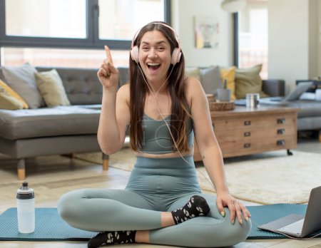 Téléchargez les photos : Jeune femme adulte pratiquant le yoga se sentant comme un génie heureux et excité après avoir réalisé une idée, levant joyeusement le doigt, eureka! - en image libre de droit
